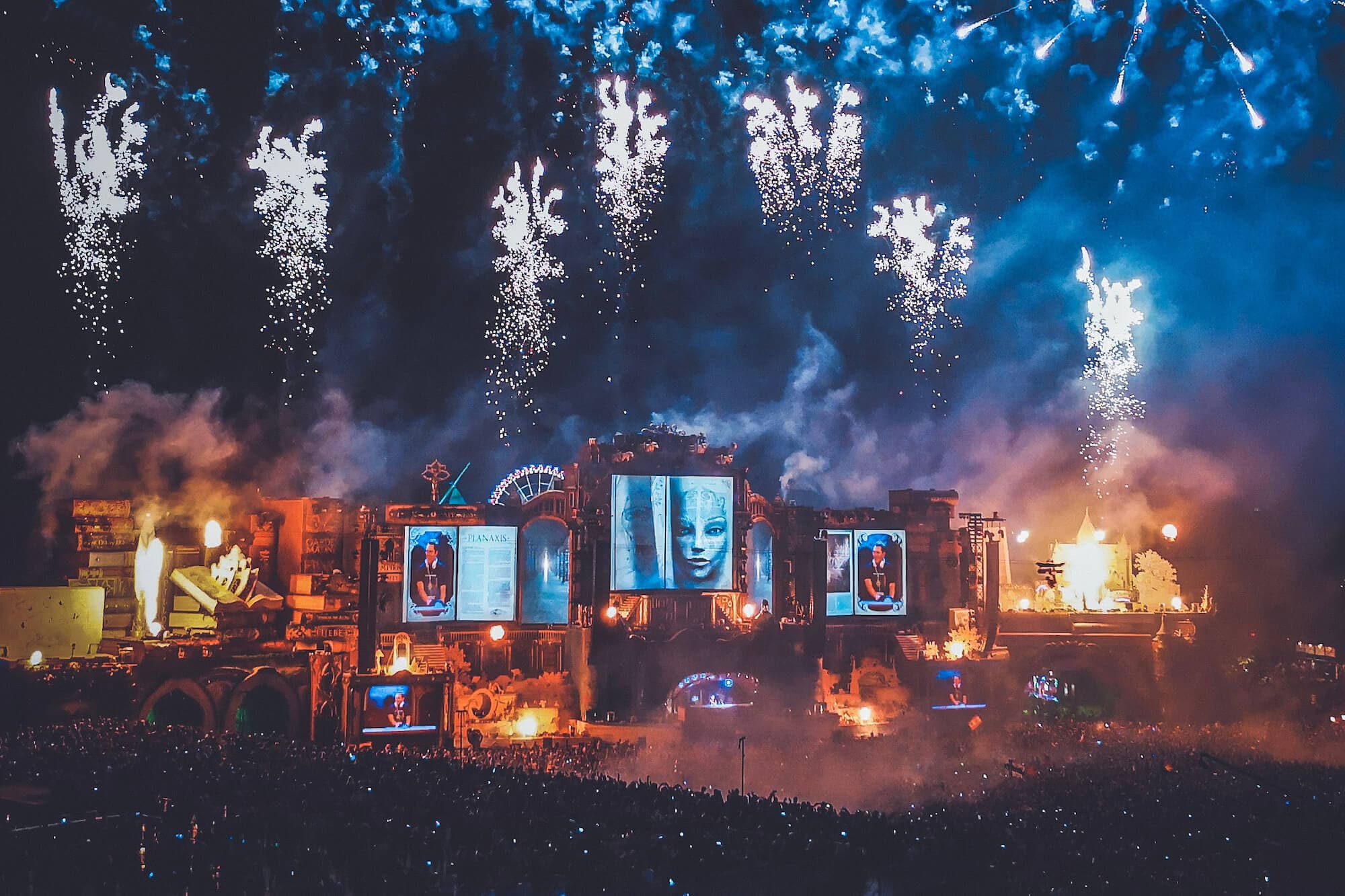 Illuminating the night sky, spectacular fireworks explode above an ecstatic crowd at the iconic Tomorrowland Festival. Photo by Daniels Joffe.