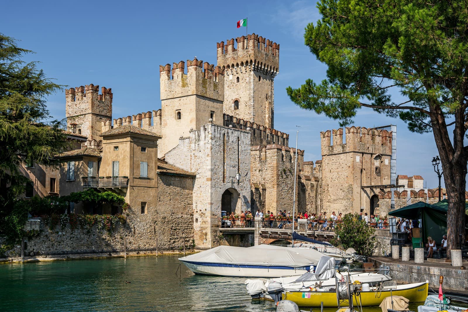 The medieval Scaliger Castle of Sirmione rises majestically over Lake Garda’s turquoise waters, its crenellated towers and stone walls standing guard over the charming lakeside town.