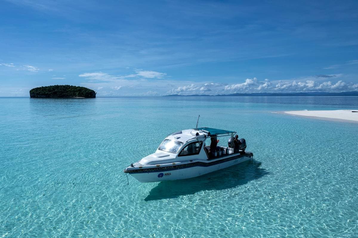 Boat captain waiting for divers during the surface interval between dives on a small island near the Cape Kri dive site in Raja Ampat.