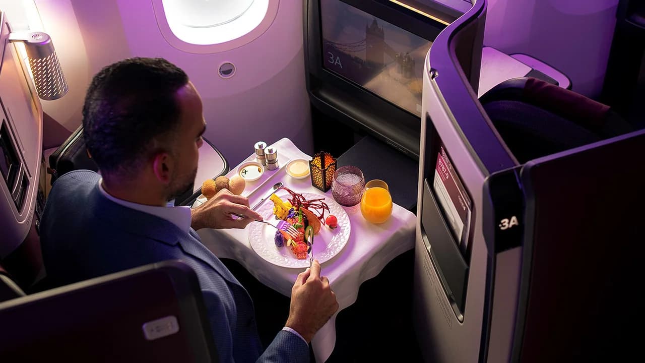 QSuite dine-on-demand meal service — gourmet dining on fine china with white linen at 35,000 feet